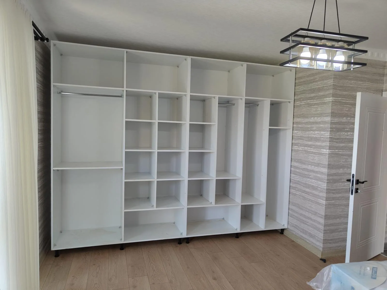 Duvar boyunca uzanan beyaz açık raf ve dolap ünitesi