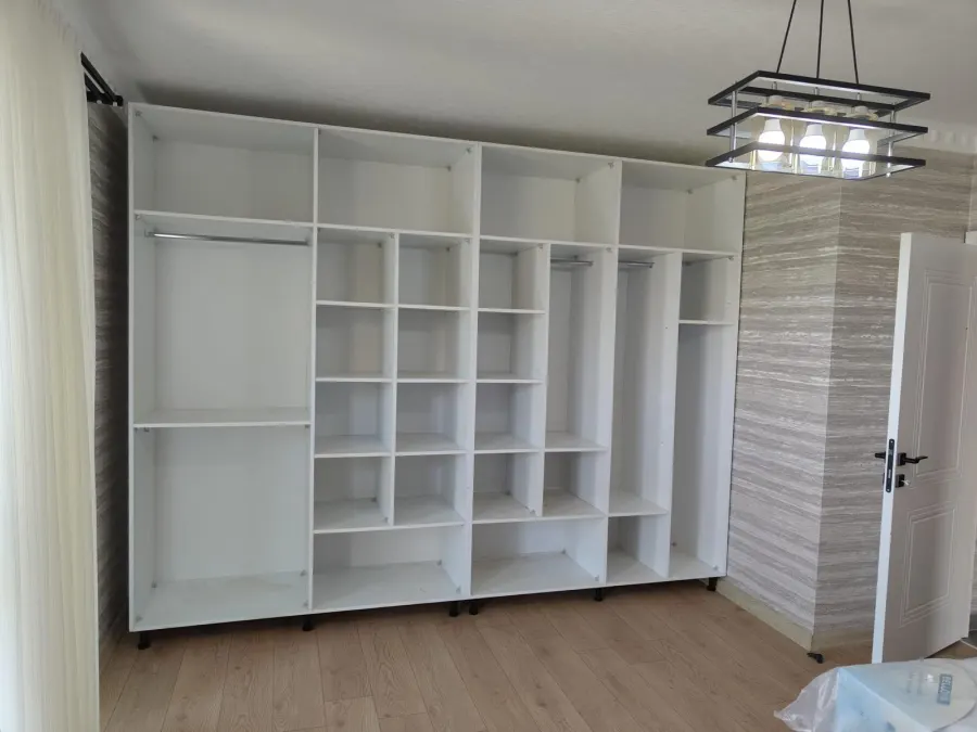 Duvar boyunca uzanan beyaz açık raf ve dolap ünitesi